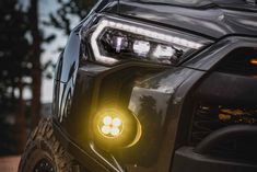 the front end of a black truck with its lights on and headlamps glowing