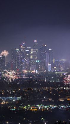 fireworks are lit up in the night sky over a cityscape with skyscrapers