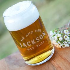 a glass of beer sitting on top of a wooden table next to a bouquet of flowers