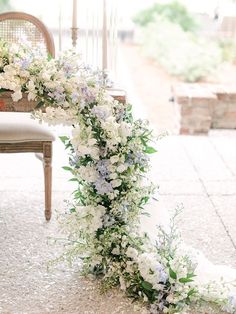 a wedding arch decorated with flowers and greenery on the ground in front of a chair