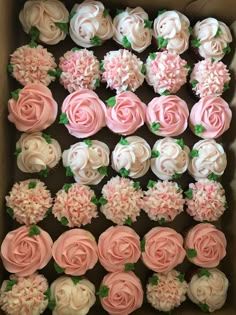 a box filled with cupcakes covered in pink and white frosting flowers on top of each other