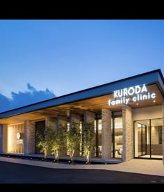 the front entrance to kuroda family clinic at night with lights on and trees outside