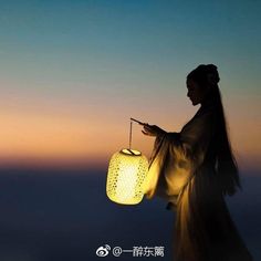 a woman holding a lantern in her hand