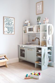 a child's play kitchen with toys on the floor and in front of it