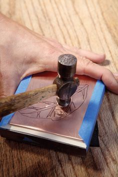 a person is using a metal stamper on a book