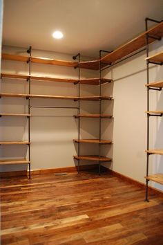 an empty walk in closet with wooden shelves