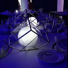 a room filled with lots of tables covered in plates and silverware on top of a blue table cloth