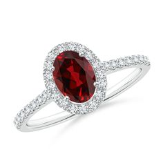 a ring with a large red stone surrounded by diamonds on the sides and an oval shaped halo