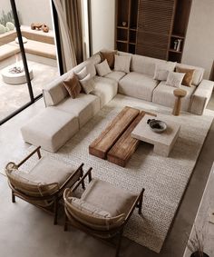 a living room with white couches and wooden tables on the floor in front of large windows