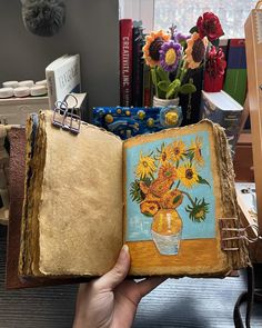 an open book with sunflowers in a vase painted on it's cover