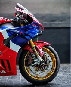 a red, white and blue motorcycle parked in front of a building