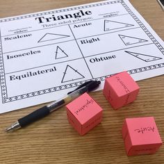 three pink cubes sitting on top of a table next to a pen and paper