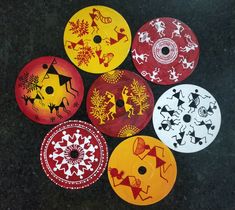 six different colored discs with designs on them sitting on a black surface, one is yellow and the other is red