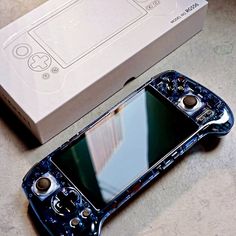 an open cell phone sitting on top of a table next to a box with buttons