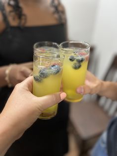 two people holding up glasses filled with drinks