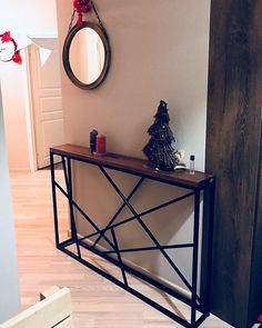 a wooden table sitting in the middle of a room next to a mirror and christmas tree