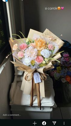 a bouquet of flowers sitting on top of a white box next to a window sill