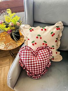 two heart shaped pillows sitting on top of a chair next to a vase with flowers