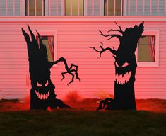 two halloween decorations in front of a pink house