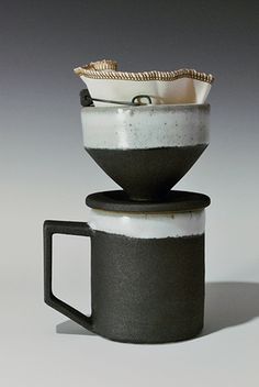 two black and white coffee mugs stacked on top of each other in front of a gray background