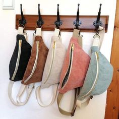 four purses hanging on a coat rack with hooks