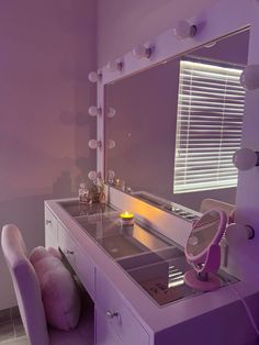 a vanity with a mirror, stool and candle on it in a room that has purple walls