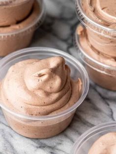 three plastic cups filled with chocolate pudding on top of a marble countertop next to each other