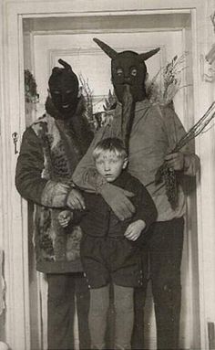 an old black and white photo shows three people in costumes with masks on their heads