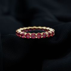 a gold ring with red stones on it sitting on a black cloth, close up