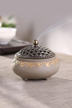 a silver teapot with steam coming out of it sitting on a table next to a bowl