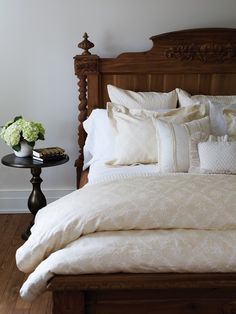 a bed with white sheets and pillows on top of it next to a night stand