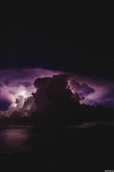 the sky is filled with purple clouds as it glows in the dark night time