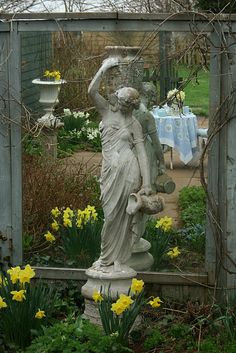 a statue is in the middle of a garden with daffodils around it