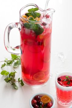 a pitcher filled with liquid and garnish next to two bowls full of fruit