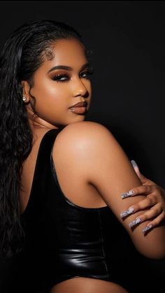 a woman with long hair wearing a black top and silver nail polish on her nails