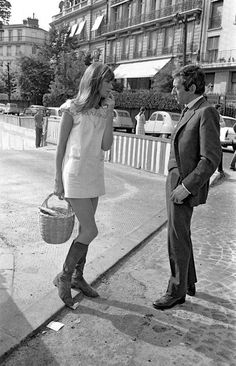 a man standing next to a woman on the side of a road holding a basket