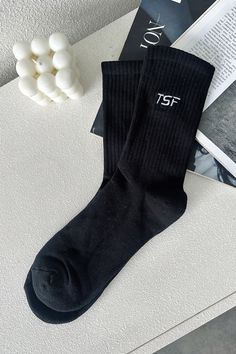 Millie Socks are designed to provide optimal comfort and style. They offer mid-calf coverage and ribbed ankles that add an extra touch of style. The iconic TSF logo is featured prominently to provide a chic look to any outfit. Trendy Cotton Socks With Letter Print, Black Socks For Fall Streetwear, Trendy Letter Print Cotton Socks, Trendy Cotton Letter Print Socks, Black Fall Streetwear Socks, Casual Mid-calf Ribbed Socks, Black Ribbed Stretch Socks, Black Stretch Ribbed Socks, Black Stretch Socks For Streetwear