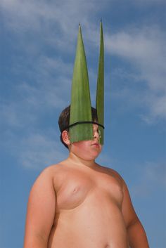 a man with two large green leaves on his head, and one big naked body