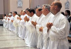 a group of men standing in front of each other with their hands together and praying