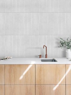 a modern kitchen with wooden cabinets and white tile backsplash, copper faucet