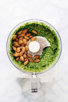 a food processor filled with pesto and almonds