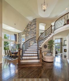 a living room filled with furniture and a spiral stair case in front of a stone wall