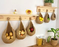 there are several baskets hanging on the wall with fruits and vegetables in them, as well as two potted plants