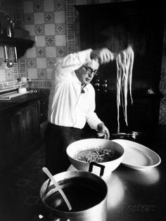 an old photo of a man in the kitchen preparing food with noodles and sauces