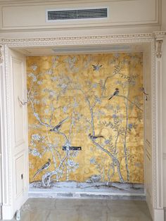 a room with yellow wallpaper and birds painted on the walls in front of it