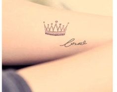 a woman's arm with a crown tattoo on the left side of her arm