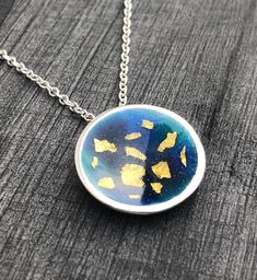 "This enamel pendant is made from Sterling Silver with enamel and fine gold detail. The cup-shaped pendant has beautiful blue and turquoise enamels and 22ct gold foil detail sealed securely. It has a flat, silver circumference and measures approx. 2cms in diameter. Inspired by an atlas this minimalist piece had a contemporary feel. The pendant hangs on an 18\" Sterling Silver chain and matching studs are also available." Yellow Gold Enamel Oval Pendant Necklaces, Gold Enamel Necklaces With Detachable Pendant, Gold Enamel Round Pendant Necklace, Gold Enamel Medallion Necklace, Gold Enamel Necklace With Detachable Pendant, Handmade Enamel Round Necklaces, Handmade Round Enamel Necklaces, Handmade Enamel Round Necklace, Handmade Round Enamel Necklace