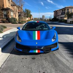 a blue sports car parked on the side of a road in front of some houses