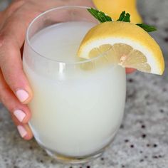 a person holding a glass with some lemons in it