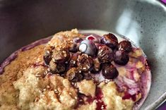 a bowl filled with dessert and toppings on top of a purple table cloth next to a spoon